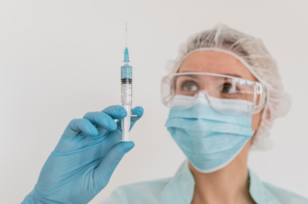 Photo front view of female doctor with gloves holding vaccine and syringe