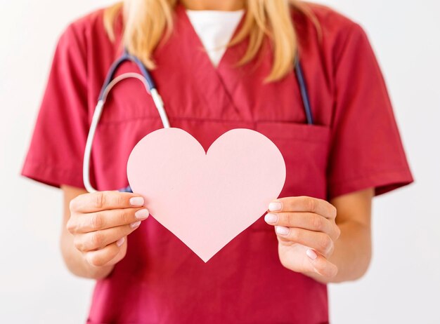 Photo front view female doctor with stethoscope holding paper heart