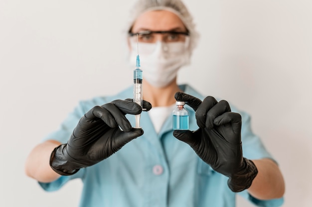 Photo front view of female doctor with syringe and vaccine