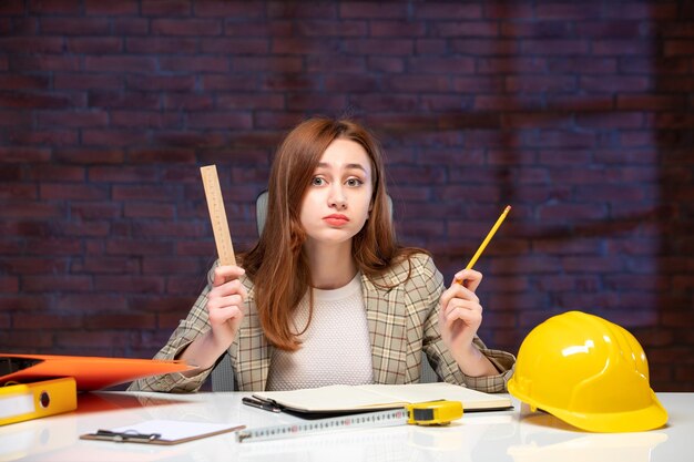 front view female engineer sitting behind her working place in construction site job agenda builder plan contractor business success corporate property