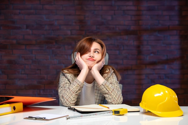 front view female engineer sitting behind her working place in construction site job agenda business corporate builder contractor property plan