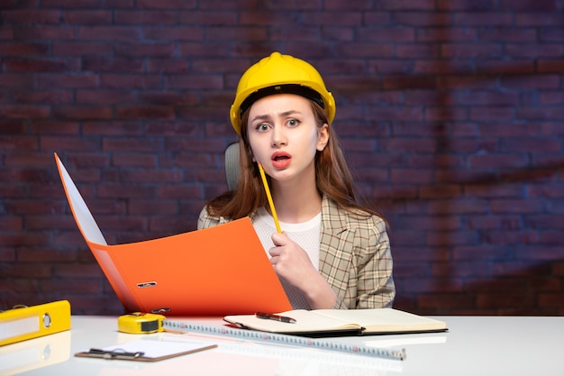 front view female engineer sitting behind her working place working with documents job corporate success business contractor property plan builder