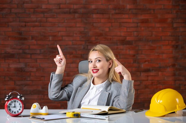 Assistente tecnico femminile di vista frontale che si siede dietro il suo posto di lavoro