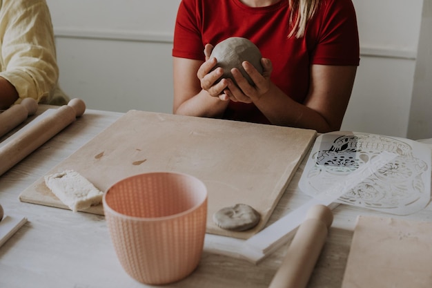 Front view of female potter kneading softly clay on worktop with her hands