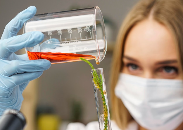 Foto vista frontale del ricercatore femminile con mascherina medica in laboratorio