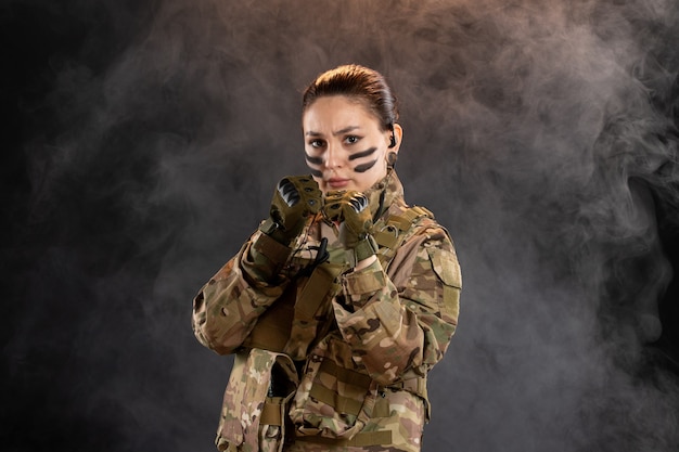 Front view of female soldier in camouflage black smoky wall