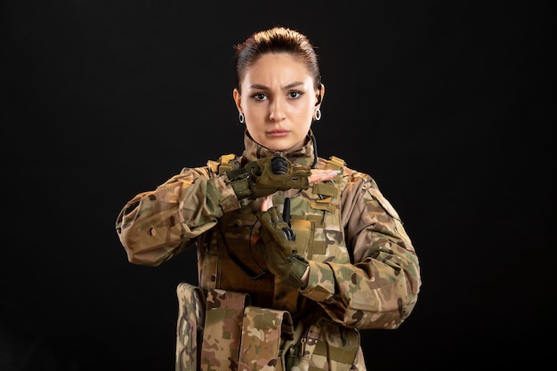 Front view of female soldier in camouflage black wall