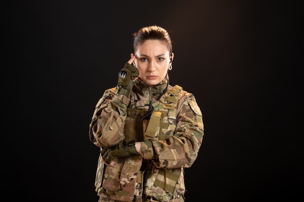 Front view of female soldier in camouflage on a black wall