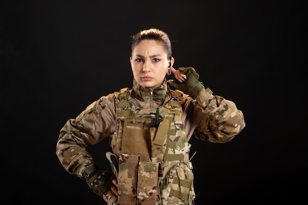 Front view of female soldier in camouflage on black wall