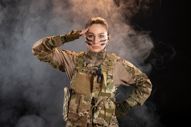 Front view of female soldier in camouflage on dark wall