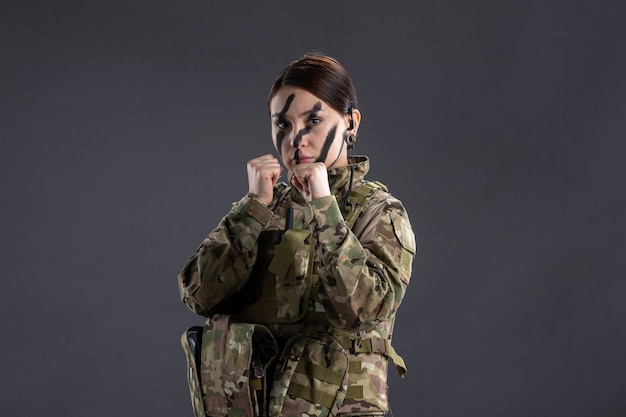 Front view of female soldier in camouflage on dark wall