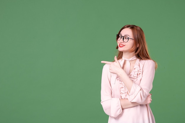 Insegnante femminile di vista frontale in camicetta rosa su sfondo verde scuola colore biblioteca college lavoro studente giovane libro lezione lavoro