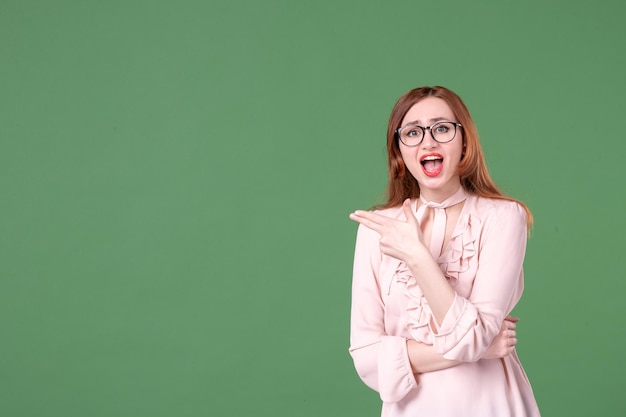 Front view female teacher in pink blouse on green background school color library college job woman student young book lesson work