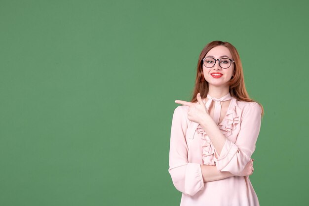 Front view female teacher in pink blouse on green background school color library college job woman young book lesson work