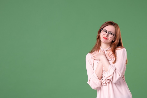 Front view female teacher in pink blouse posing on green background job school woman color book young student college work lesson