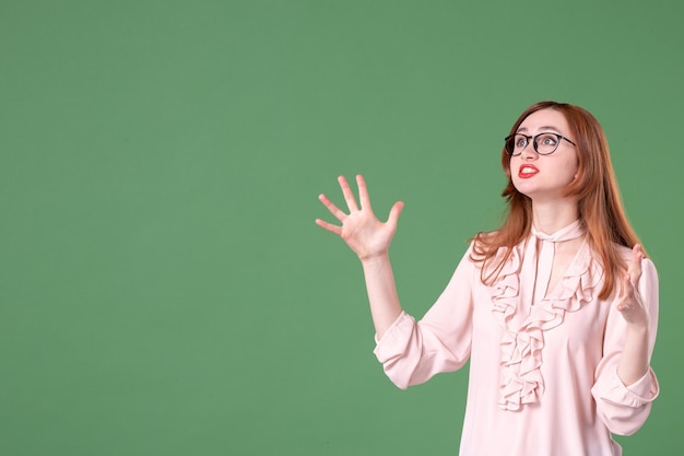 Front view female teacher in pink blouse posing on green