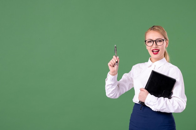 Front view female teacher posing with notepad and pen on green background woman lesson work school study book money student document