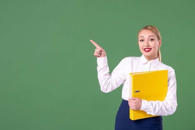 Front view female teacher with yellow files on green background lesson work student university study library uniform school book