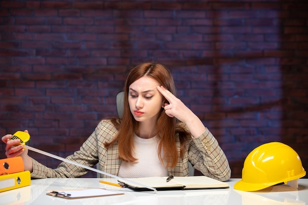 front view female worker in construction site holding tape measure and writing notes agenda engineer corporate business job plan manager