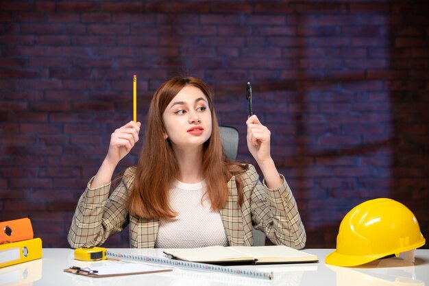 front view female worker in construction site sitting behind table agenda job engineer business manager corporate plan working