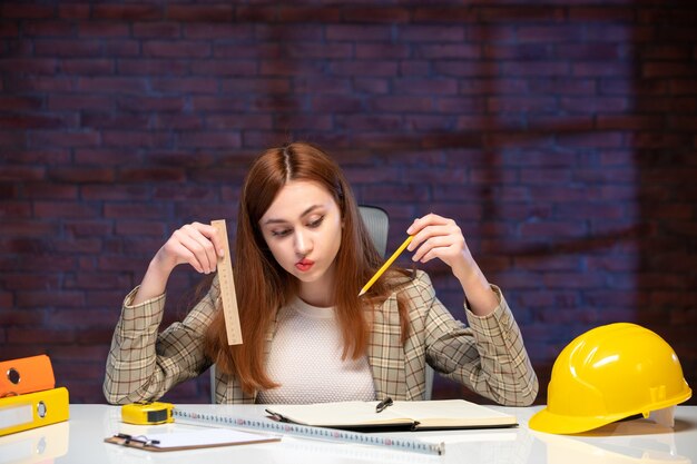 テーブルアジェンダの後ろに座っている建設現場の女性労働者の正面図ジョブエンジニアビジネスプラン企業