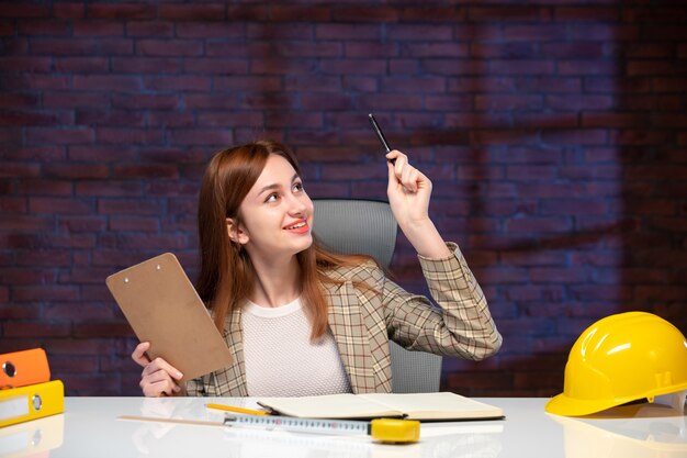 front view female worker in construction site sitting behind table with documents job corporate plan manager engineer project agenda business