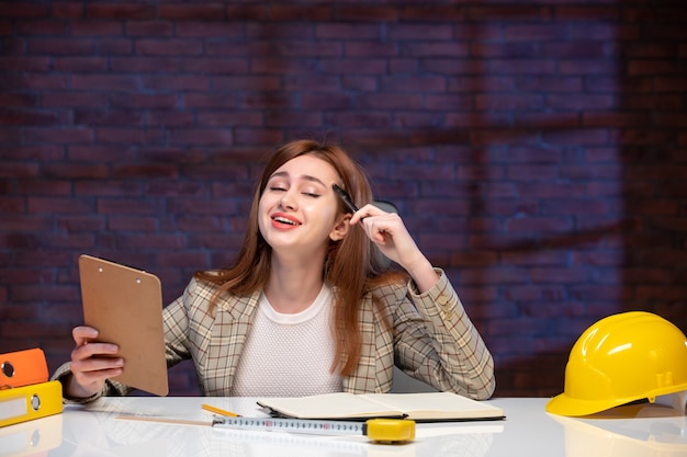 front view female worker inside construction site sitting behind table with documents job corporate contractor plan manager engineer project