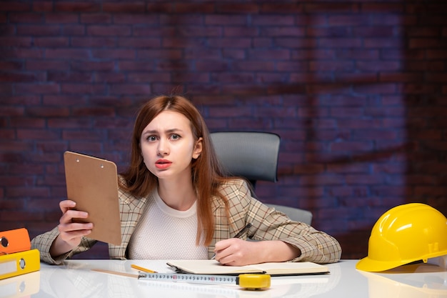 front view female worker inside construction site sitting behind table with documents job corporate contractor project plan manager engineer