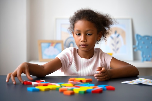 Photo front view focused girl making puzzle at table