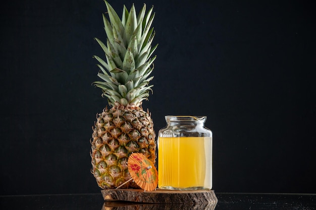 front view fresh pineapple juice in carafe on wood board on black background