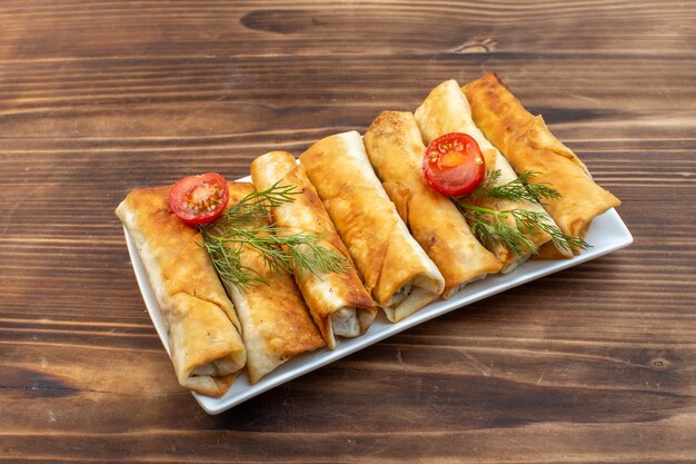 front view fried greens pastries with greens and tomatoes inside plate on brown background cooking food bake cuisine meat cake bread pastry