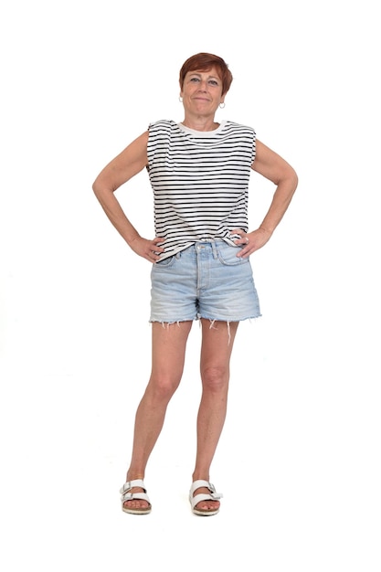 Front view of a full portrait of a middle aged woman looking at camera and arms akimbo on white background