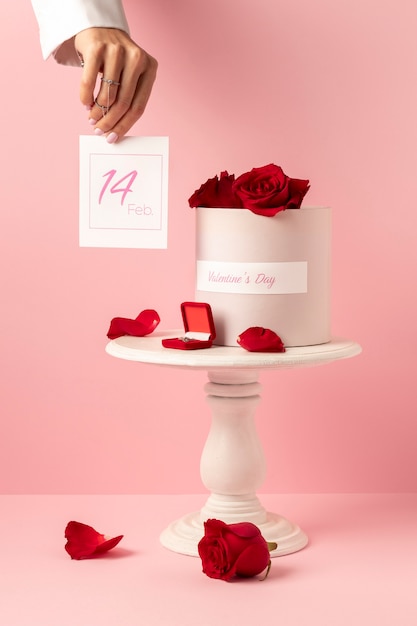 Vista frontale della confezione regalo per San Valentino con petali di rosa rossa e mano di donna