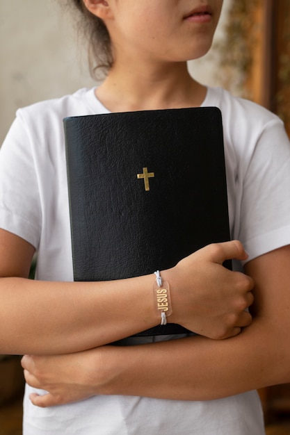 Foto ragazza di vista frontale che tiene la bibbia cristiana