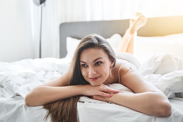 Front view of a girl lying in bed with her chin propped on her hands