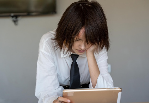 Вид спереди девушки в рубашке и галстуке, смотрящей на информацию на планшете, горизонтальный простой фон