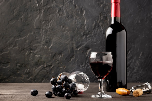 Front view glass with red wine beside wine bottle