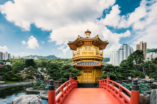 Front view the Golden pavilion temple with red bridge in Nan Lian garden, Hong Kong. Asian tourism, modern city life, or business finance and economy concept