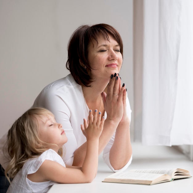 Photo front view of granddaughter and grandmother praying