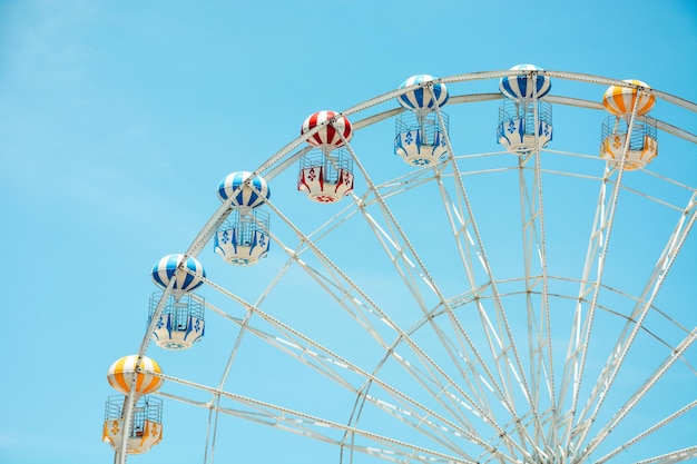 Foto vista frontale della ruota panoramica colorata a metà retrò al parco divertimenti su sfondo blu cielo