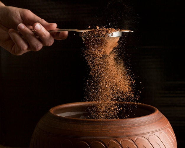 Front view hand holding strainer with cocoa powder