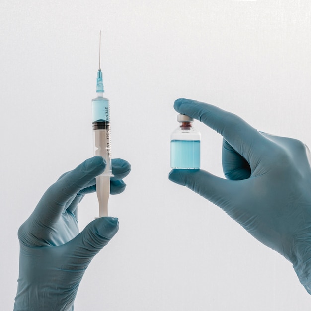 Front view of hands with gloves holding syringe with vaccine