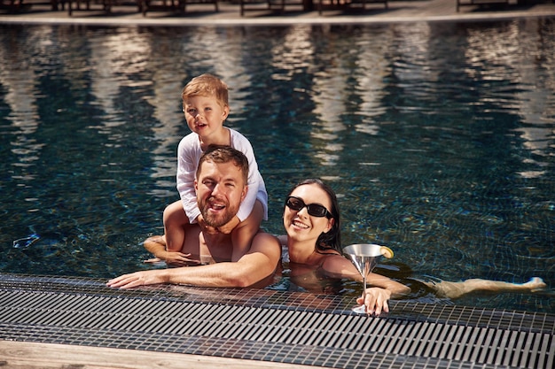 Счастливая семья отца, матери и сына в бассейне.