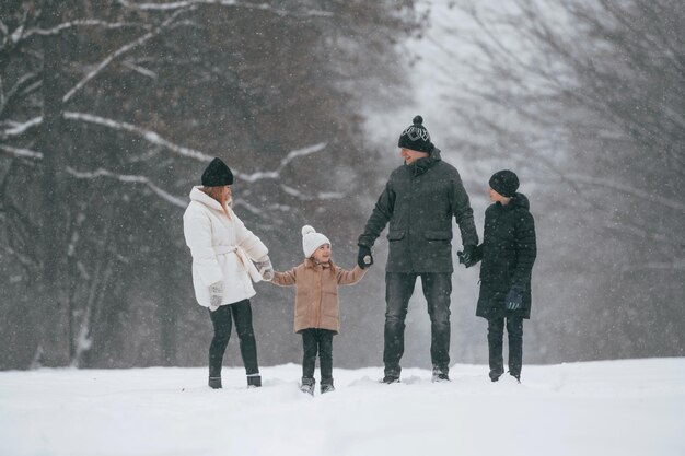 사진 앞면 으로 보이는 행복 한 가족 은 야외 에서 겨울 에 함께 눈 을 즐기고 있다