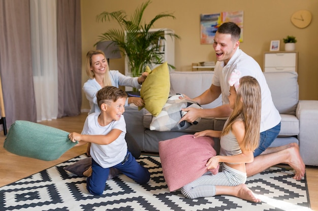 Photo front view happy family playing with pillows