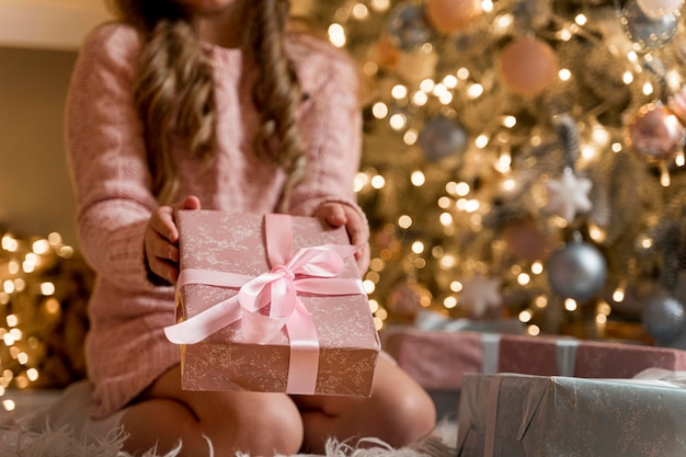 Photo front view of happy girl with gifts and christmas tree