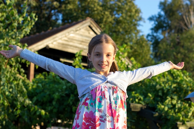 Front view of Happy teen girl with her arms wide open while standing outdoors