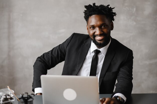 Front view head shot young smiling african american businessman looking at laptop screen