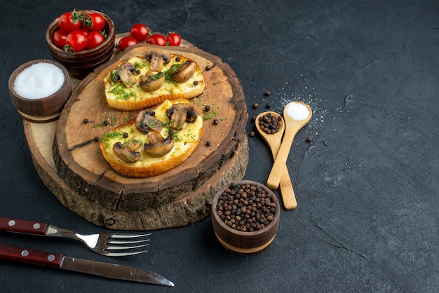 Front view of homemade tasty snack with mushrooms tomatoes salt on wooden board cutlery set on black background