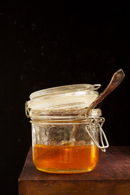 Photo front view of jar of honey with wooden spoon